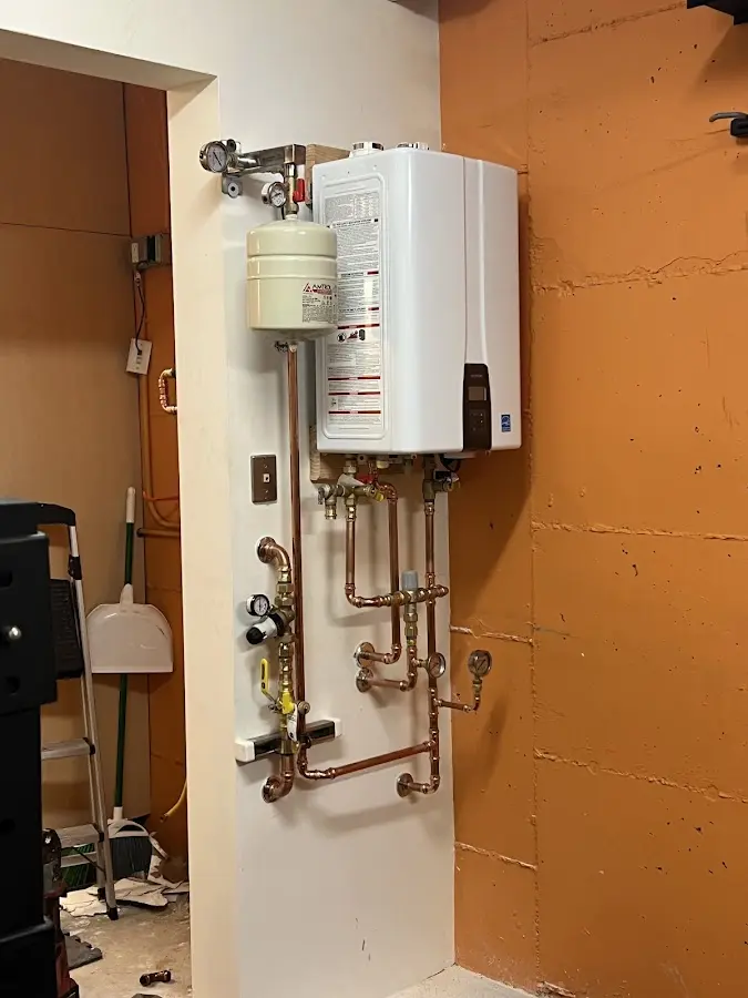 Plumbing technician inspecting water heater connections in Fruit Heights